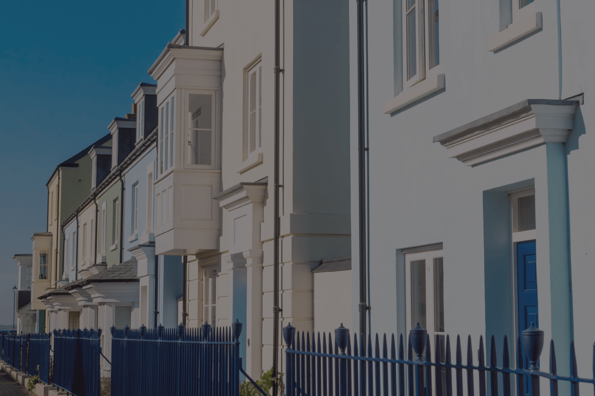 Pastel-coloured terraced houses with traditional detailing and blue railings in Poundbury, Dorchester.