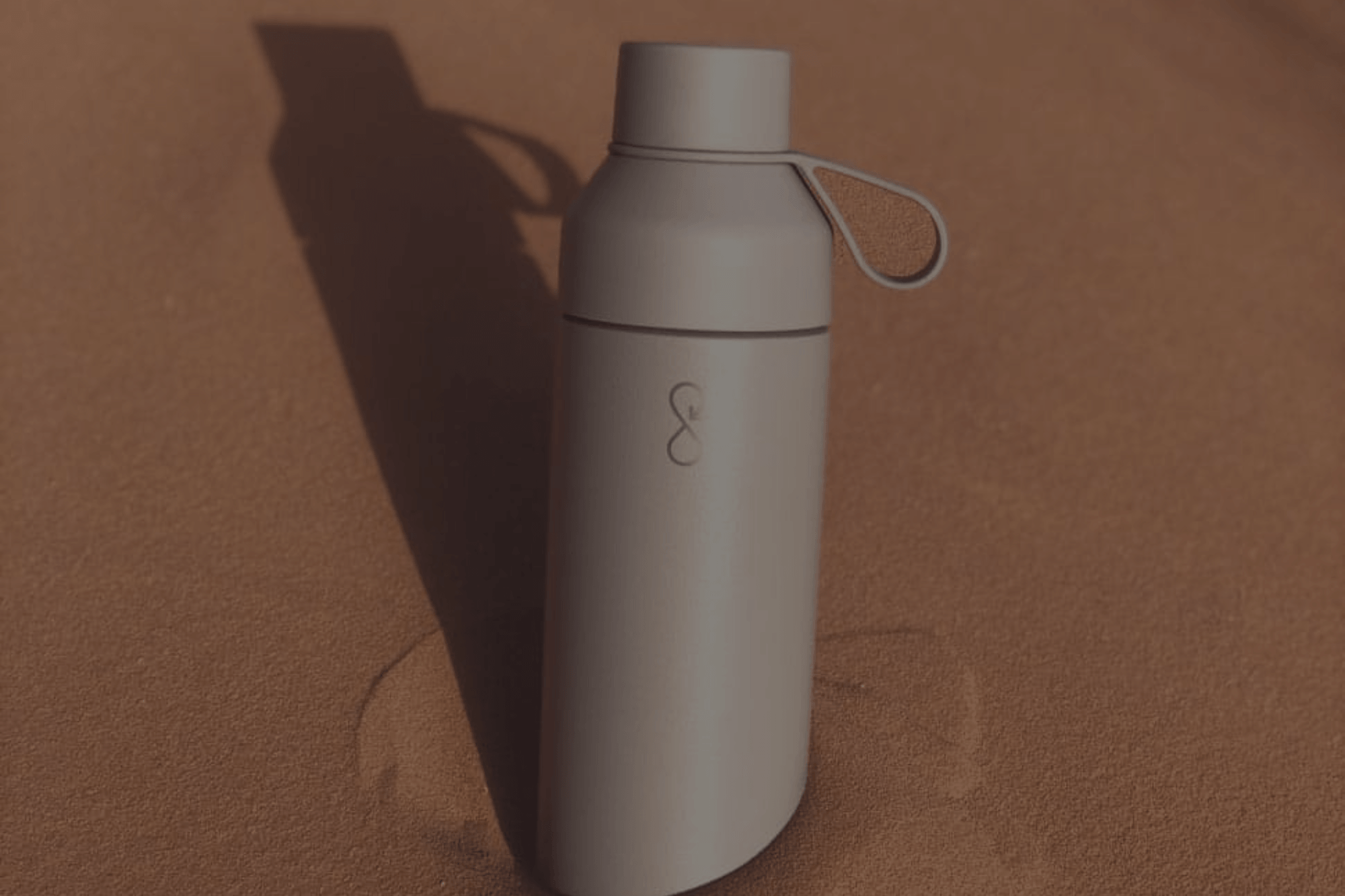 Ocean Bottle reusable water bottle on a sunlit stone surface