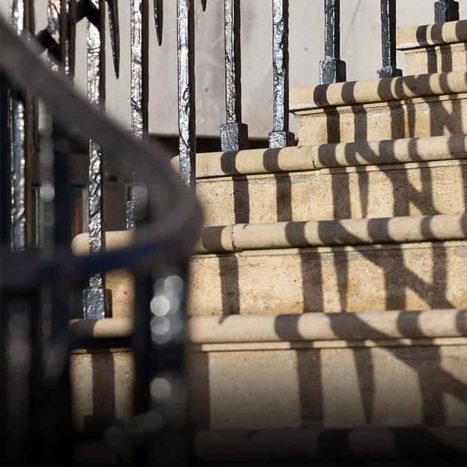 Stone steps outside Farrer & Co with black iron railings casting shadows