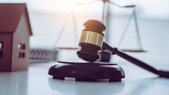 Symbolic image of a model house beside legal scales and a gavel, representing disputes over wills and financial provision under the Inheritance (Provision for Family and Dependants) Act 1975.