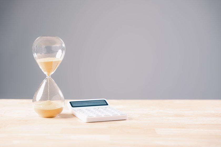 Hourglass beside calculator and coins illustrating business cashflow pressure and late payment deadlines